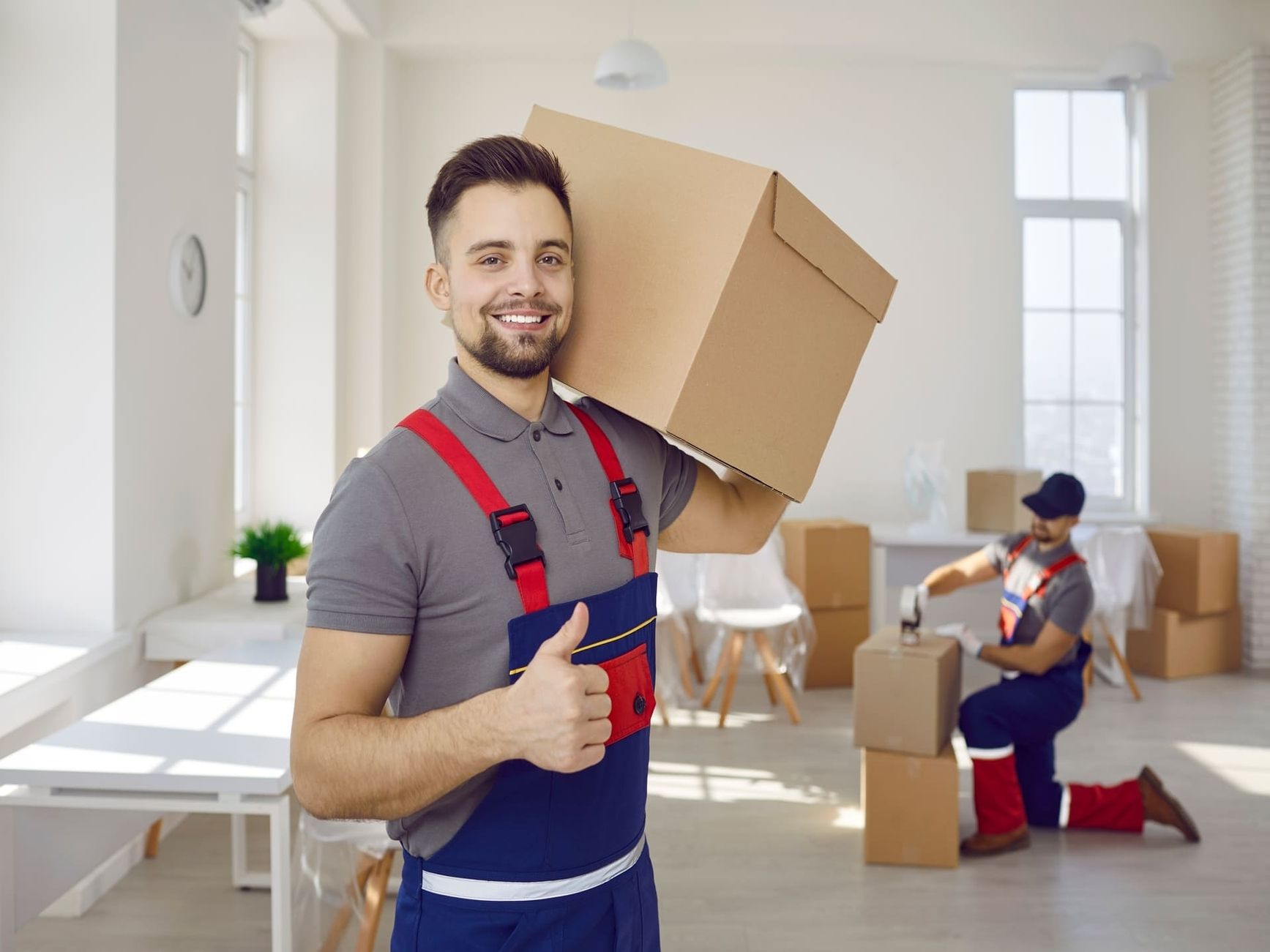 Ein Arbeiter trägt einen Karton auf der Schulter und lächelt zur Kamera